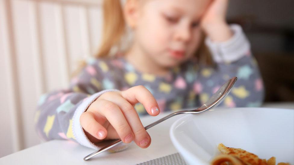 Child holding fork at the dinner table