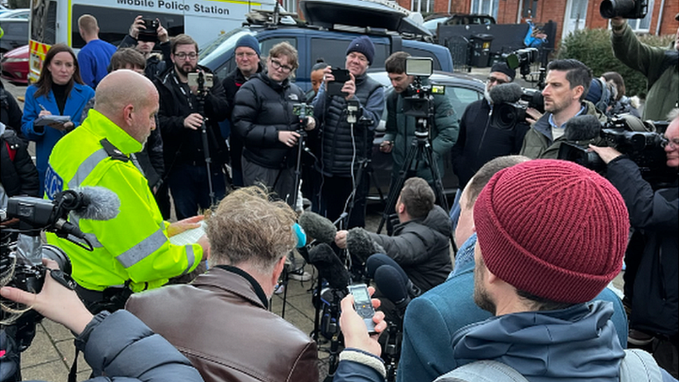 Supt Runacres surrounded by press cameras and reporters