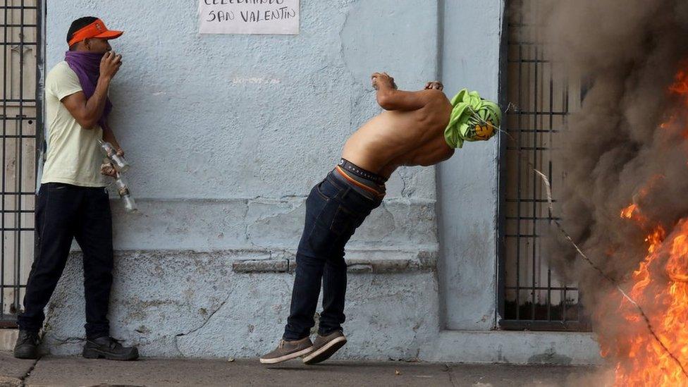 A demonstrator hits a barbed wire while clashing with security forces in Ureña, Venezuela