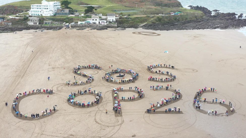 Aerial shot of SOS COP26 spelled out in the sand