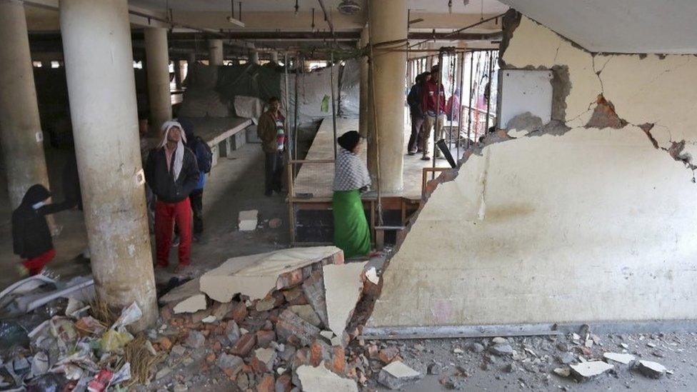 People look at a damaged building at a market place after an earthquake in Imphal, India, January 4, 2016