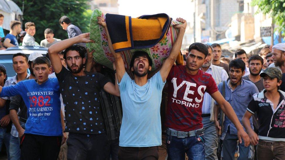 Mourners hold a funeral for members of the White Helmets rescue group who were shot dead at the office's of the group in the city of Sarmin