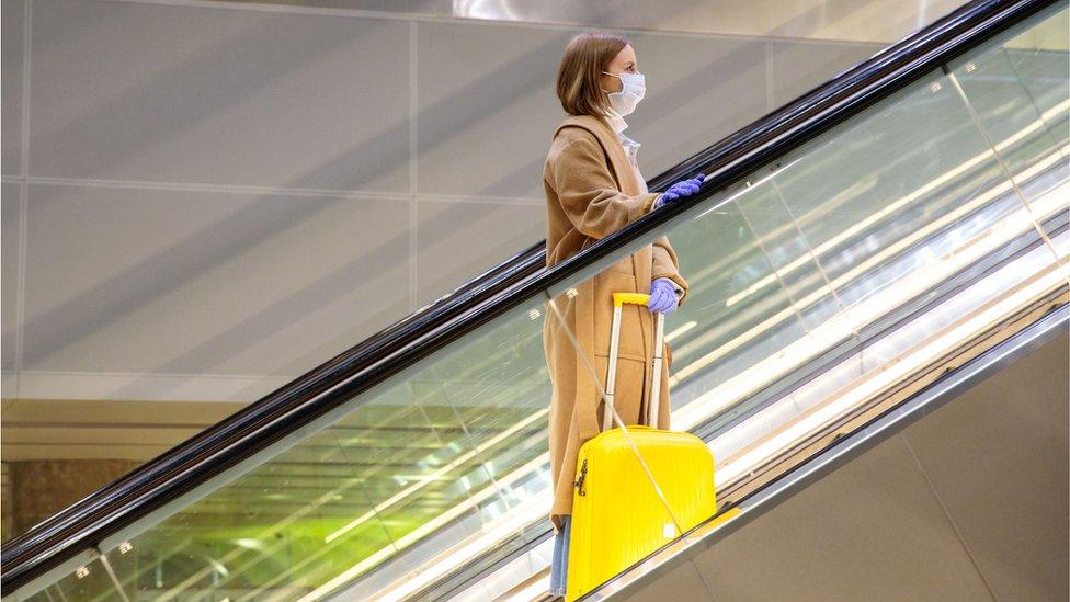 Woman stands on escalator in airport