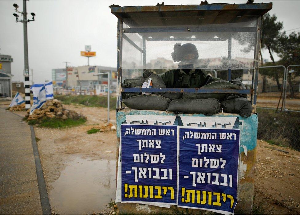 An Israeli soldier stands inside a guarding booth covered in posters with texts in Hebrew reading "Prime Minister, we bid you farewell and upon your return - sovereignty!" at a junction in the Gush Etzion Israeli settlement block in the occupied West Bank February 15, 2017