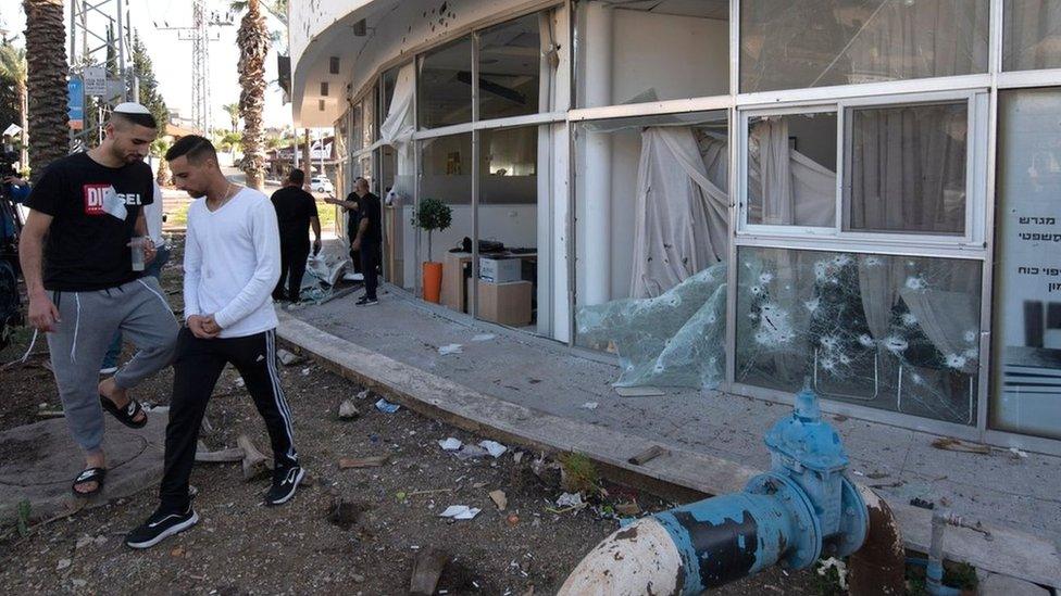 Israelis inspect a building in the northern town of Shlomi that was damaged by rocket fire from Lebanon (6 April 2023)