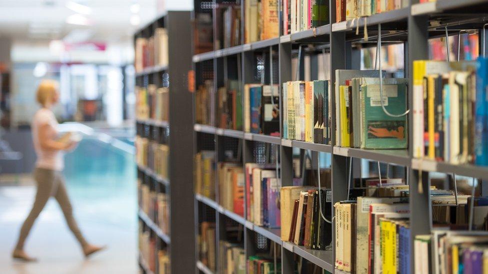 woman in library by shelf of books