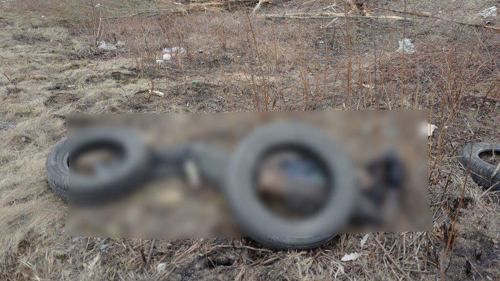 GRAPHIC: CORPSE (BLURRED) WITH TYRES