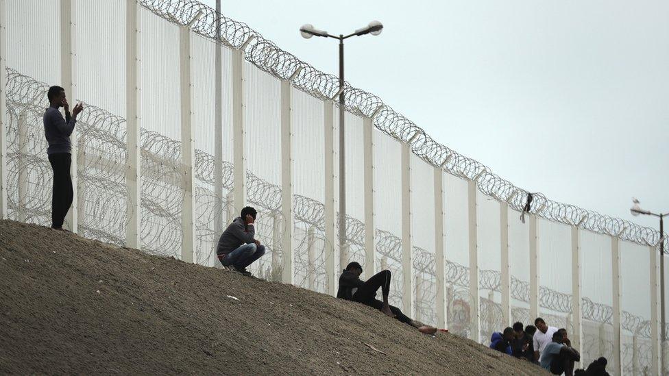 Migrants beside a fence on a motorway embankment in Calais