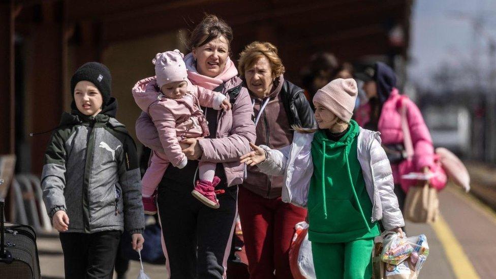 Ukrainian refugees walking on train platform in Poland