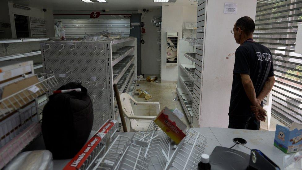 A security guard inside a looted pharmacy in Maracay