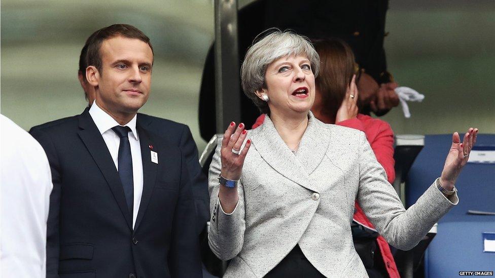 Theresa May standing next to French President Emmanuel Macron