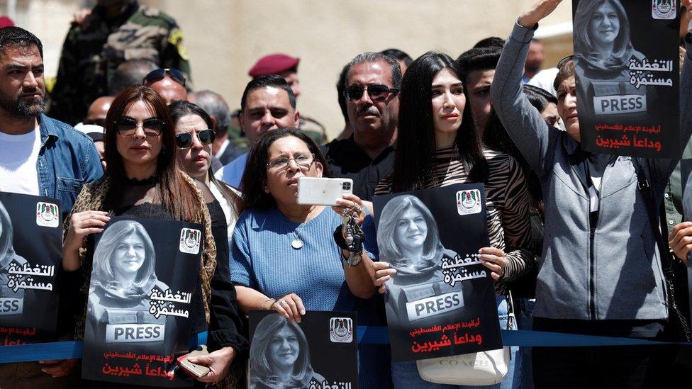 People hold up pictures of Shireen Abu Aqla during a memorial ceremony outside the Palestinian Authority's headquarters in Ramallah, in the occupied West Bank (12 May 2022)