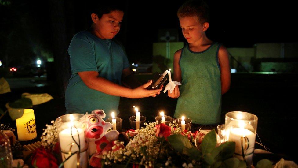 Christian Cardenas 10, helps Jaydon Johnson 8, light a candle during a vigil for the victims of a shooting at Santa Fe High School