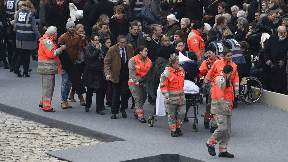 Members of the French Red Cross accompany people wounded in the Paris terror attacks, as they arrive for the "national and republican" tribute, a solemn ceremony in honour of the 130 people killed in the November 13 Paris attacks, on November 27, 2015 at the "Hotel des Invalides".