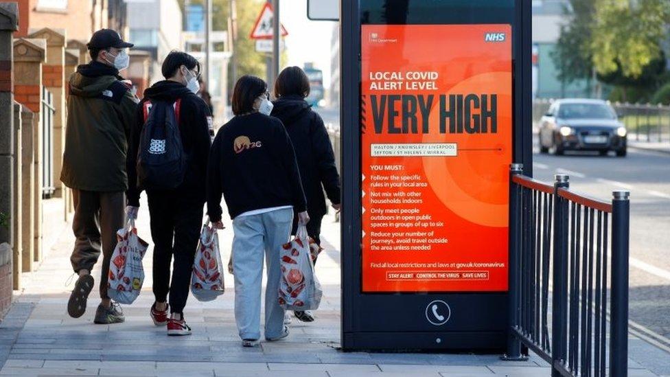 People next to a sign about coronavirus restrictions in Liverpool