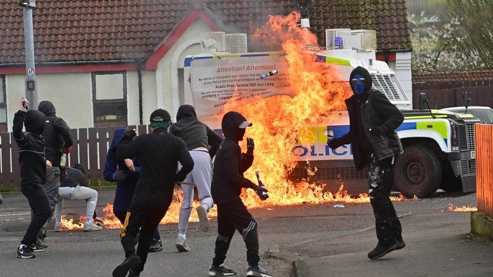 Young hooded men prepare to throw a petrol bomb at police vehicle in Londonderry