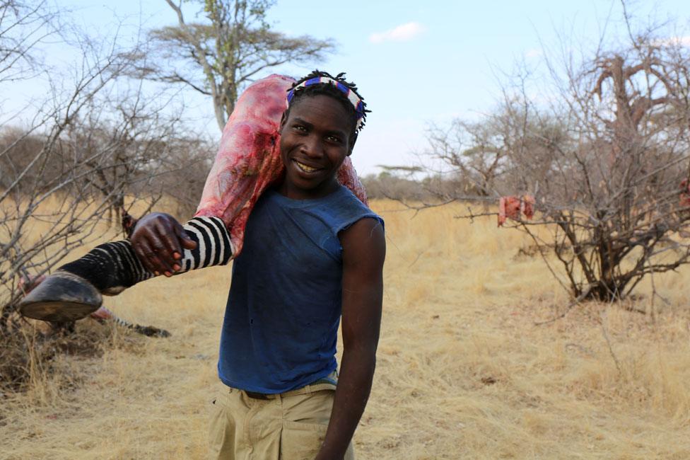 Hadza man carrying zebra leg