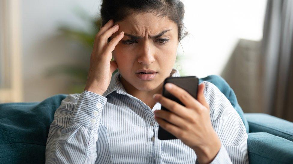 A woman looking anxiously at her phone