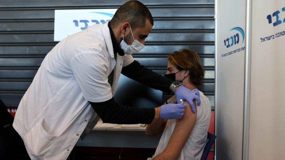 A teenager receives a vaccination against the coronavirus disease