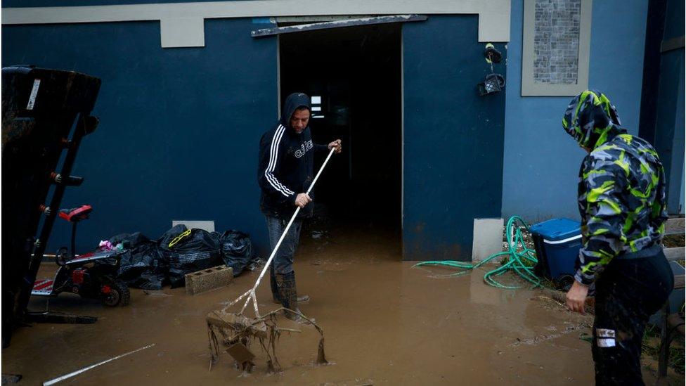 Puerto Ricans remove mud from their flooded home