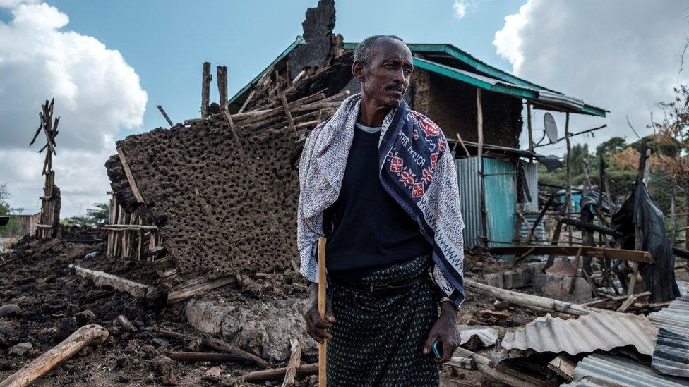 A man stands in front of his destroyed house in the village of Bisober in Ethiopia's Tigray region, on December 9, 2020.