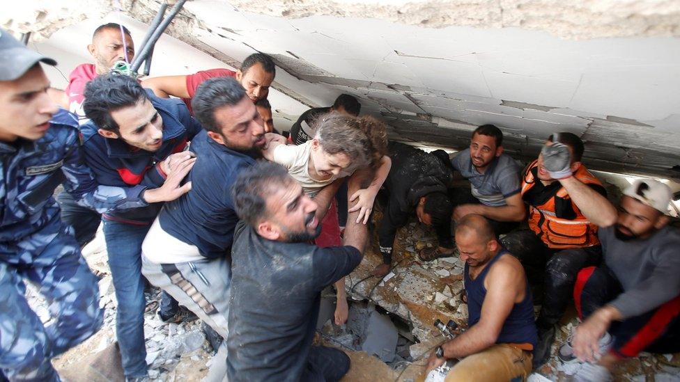 Rescuers carry Suzy Eshkuntana, 6, as they pull her from the rubble of a building at the site of Israeli air strikes, in Gaza City (16 May 2021)