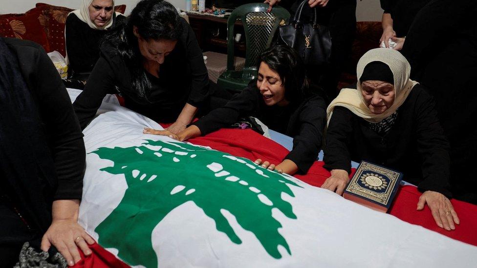 Relatives mourn beside the coffin of Reuters video journalist Issam Abdallah, who was killed by shellfire on the Lebanese side of the border (14 October 2023)