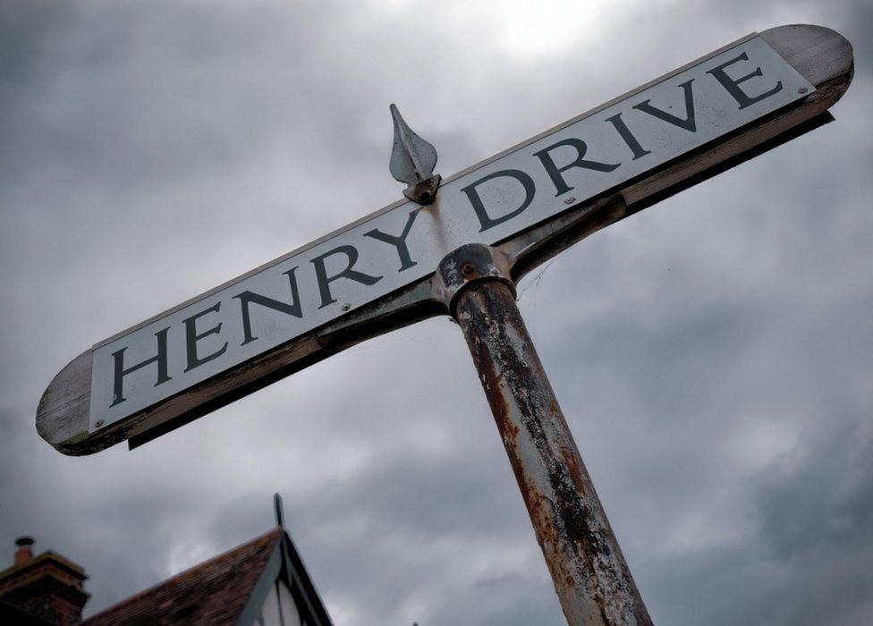 The Henry Drive sign beneath a moody grey sky.