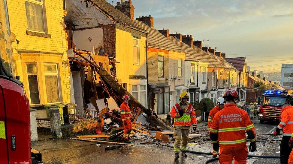 debris and crews after house explosion