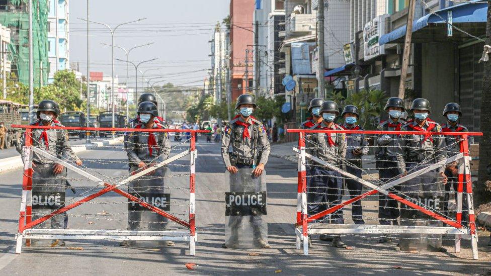 Police create a barricade and take guard on the road where protesters are protesting against the military coup.