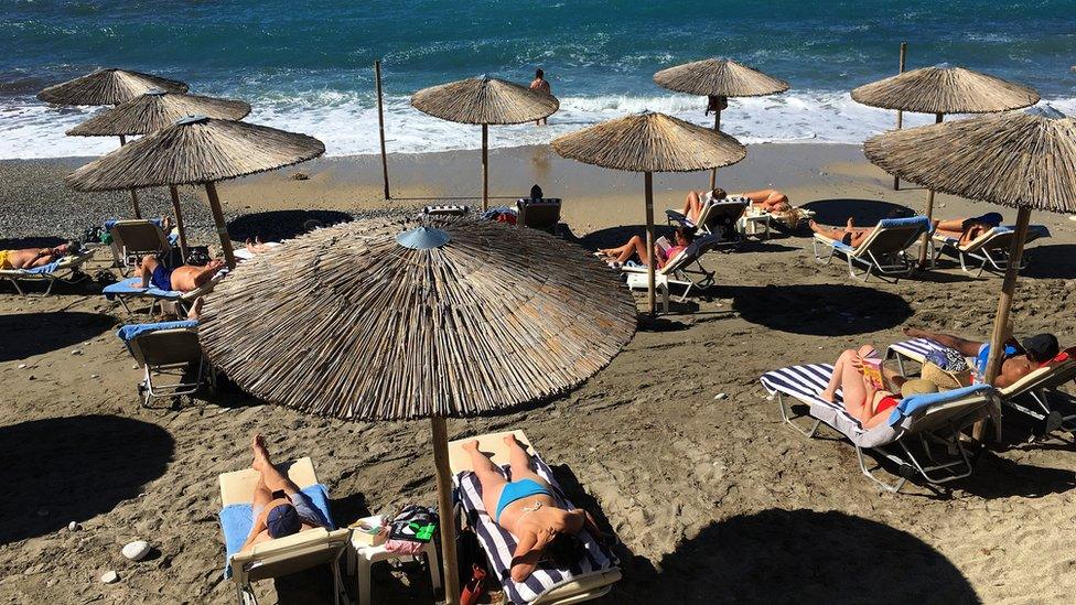 Tourists enjoy the sun on the beach at Ermones in Corfu, Greece