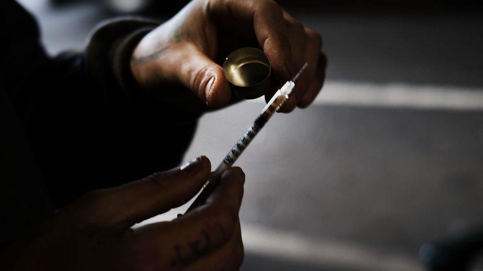 A man uses heroin under a bridge where he lives with other addicts in the Kensington section of Philadelphia