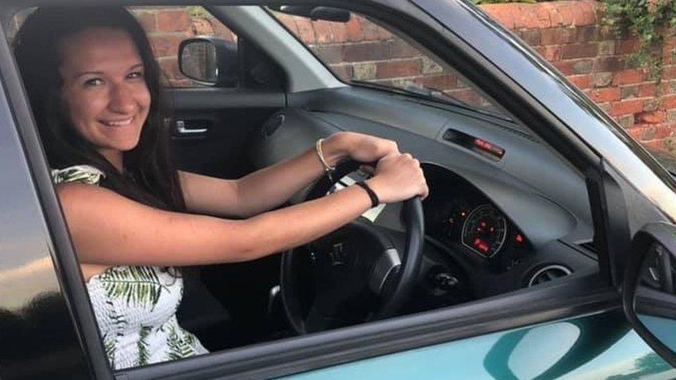 Georgia in a car with her hands on the steering wheel