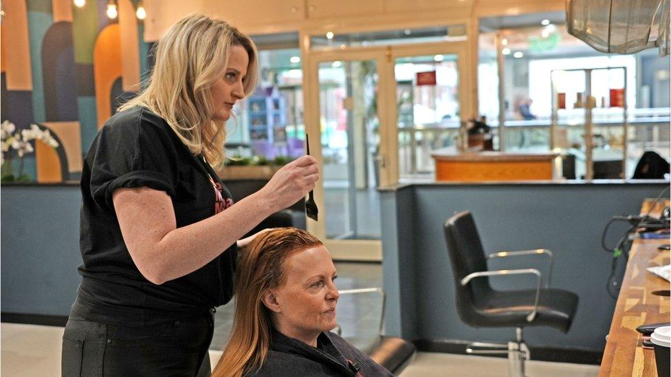 Emma touching up the roots of a client in a 'Make Menopause Matter' t-shirt