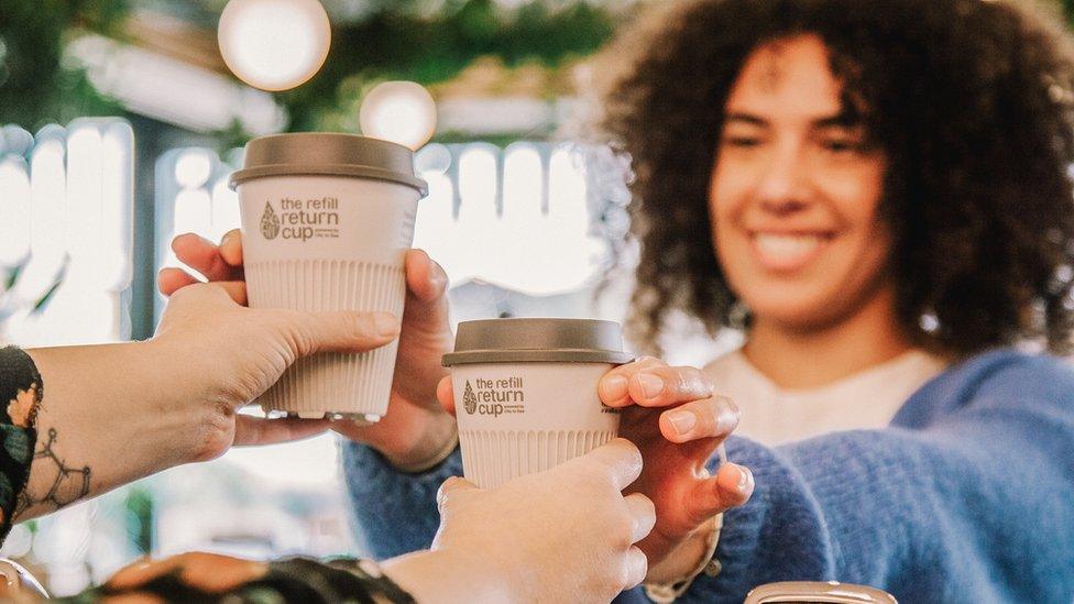 A picture of white coffee cups being handed to a woman