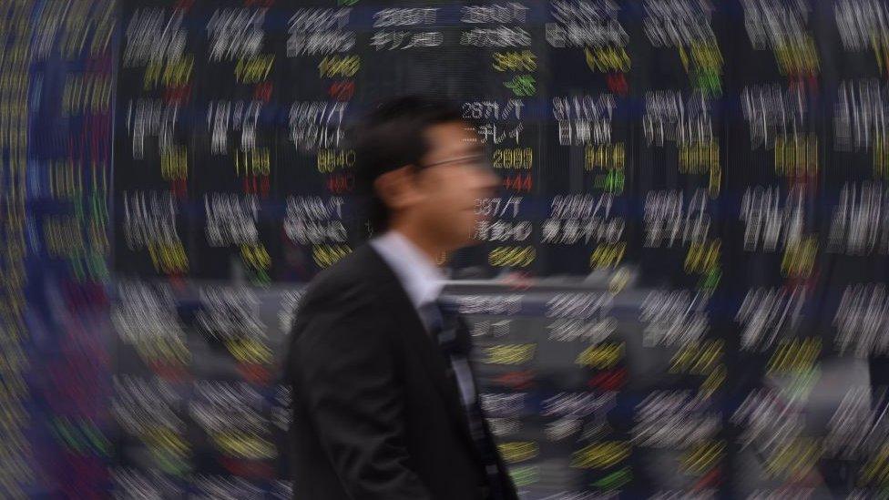 Man walking past stock boards in Tokyo