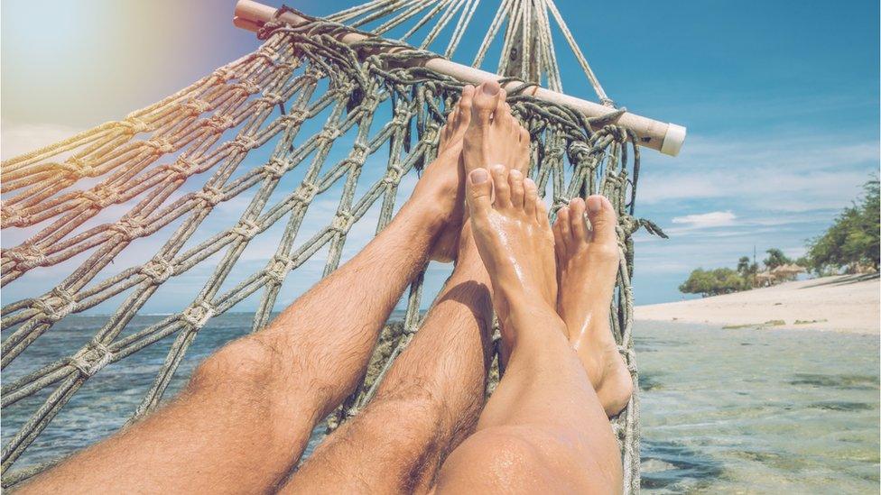 A couple lie in a hammock on an Indinesian beach