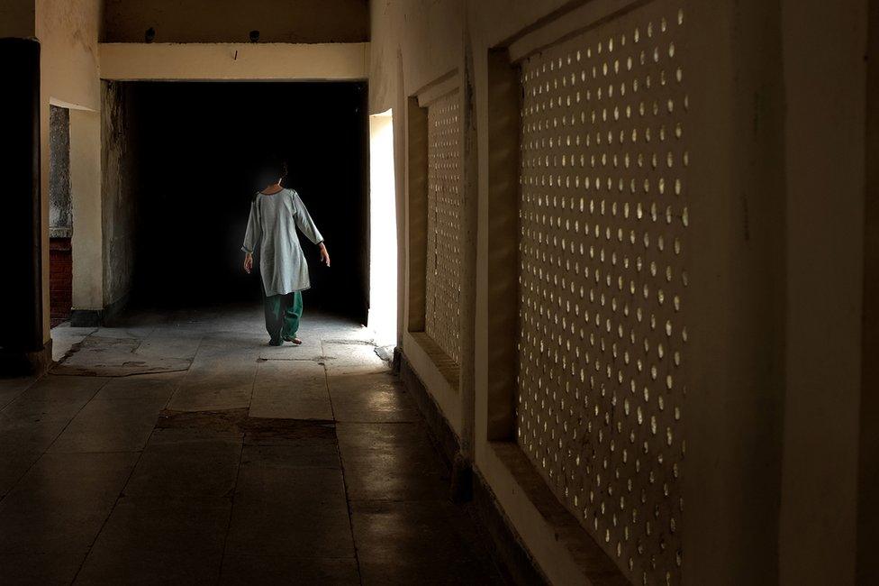 A woman, whose family institutionalised her when she displayed behavioural disorders, is seen walking down a corridor in the hospital.