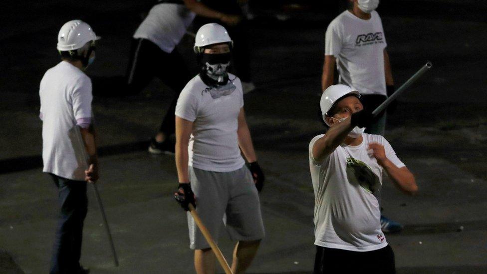 Men in white T-shirts with poles are seen in Yuen Long after attacked anti-extradition bill demonstrators at a train station, in Hong Kong, China July 22, 2019.