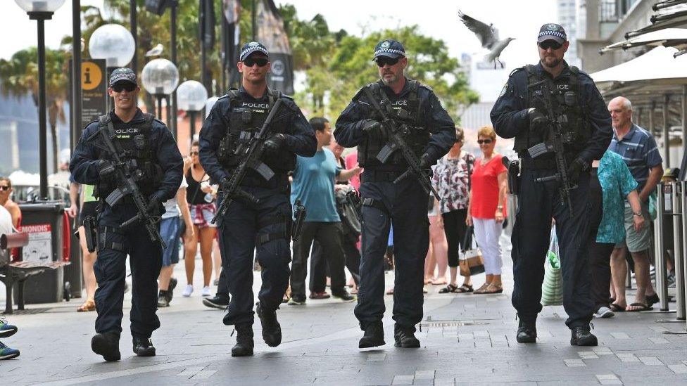 Heavily armed police officers walk along a street in Sydney