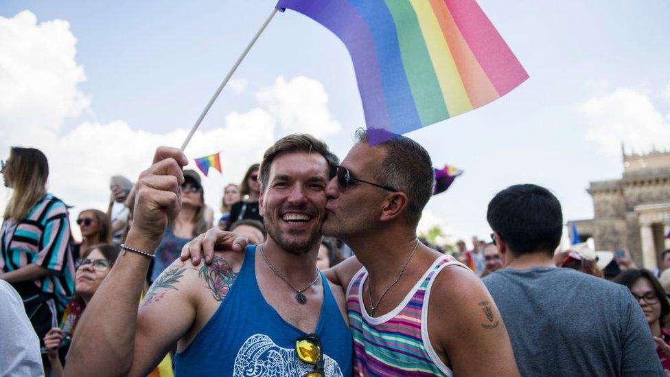 A gay couple seen kissing and waving the rainbow flag during the march