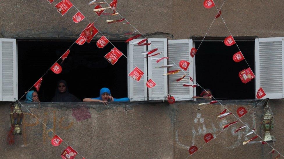 Women look from the windows of their house in the town of Toukh, Egypt