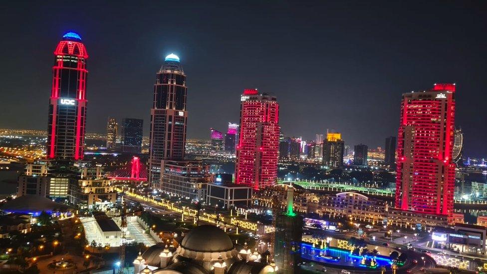 Four tall buildings light up in the colour red at night time