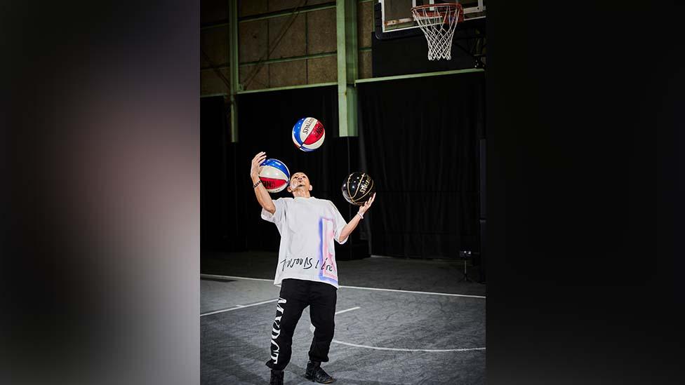 Junji Nakasone rolling basket balls in his his arms