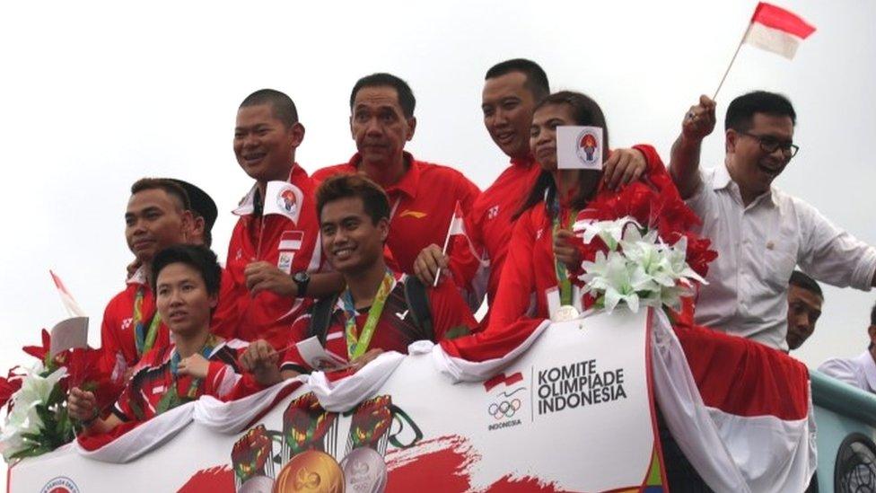 Indonesian badminton players Liliyana Natsir (back, left) and Tantowi Ahmad (back, second left wave from a bus as they parade in Cengkareng, Banten, Indonesia