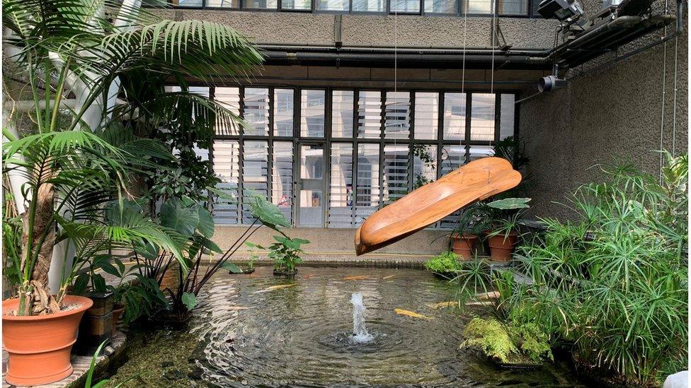 A sculpture hanging over a pond