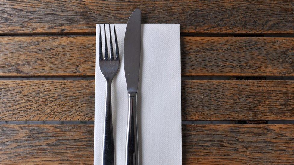 A knife, fork and napkin on a wooden table