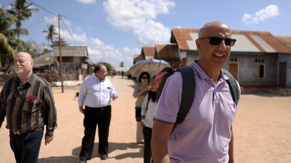 Mark Barrow and others walk in a street in Oelaba village