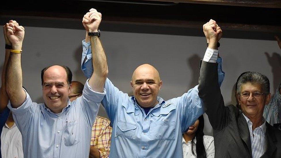 The secretary general of the 'Mesa de la Unidad Democratica' (MUD) Jesus 'Chuo' Torrealba (centre) , Venezuelan deputy for the Accion Democratica party Henry Ramos Allup (right) and deputy Julio Borges (left) hold hands after a press conference in Caracas on 29 December, 2015