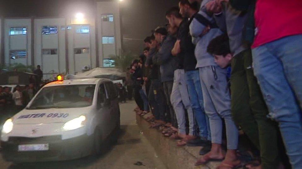 Men stand outside Nasser hospital in Khan Younis as the injured from an Israeli airstrike arrive